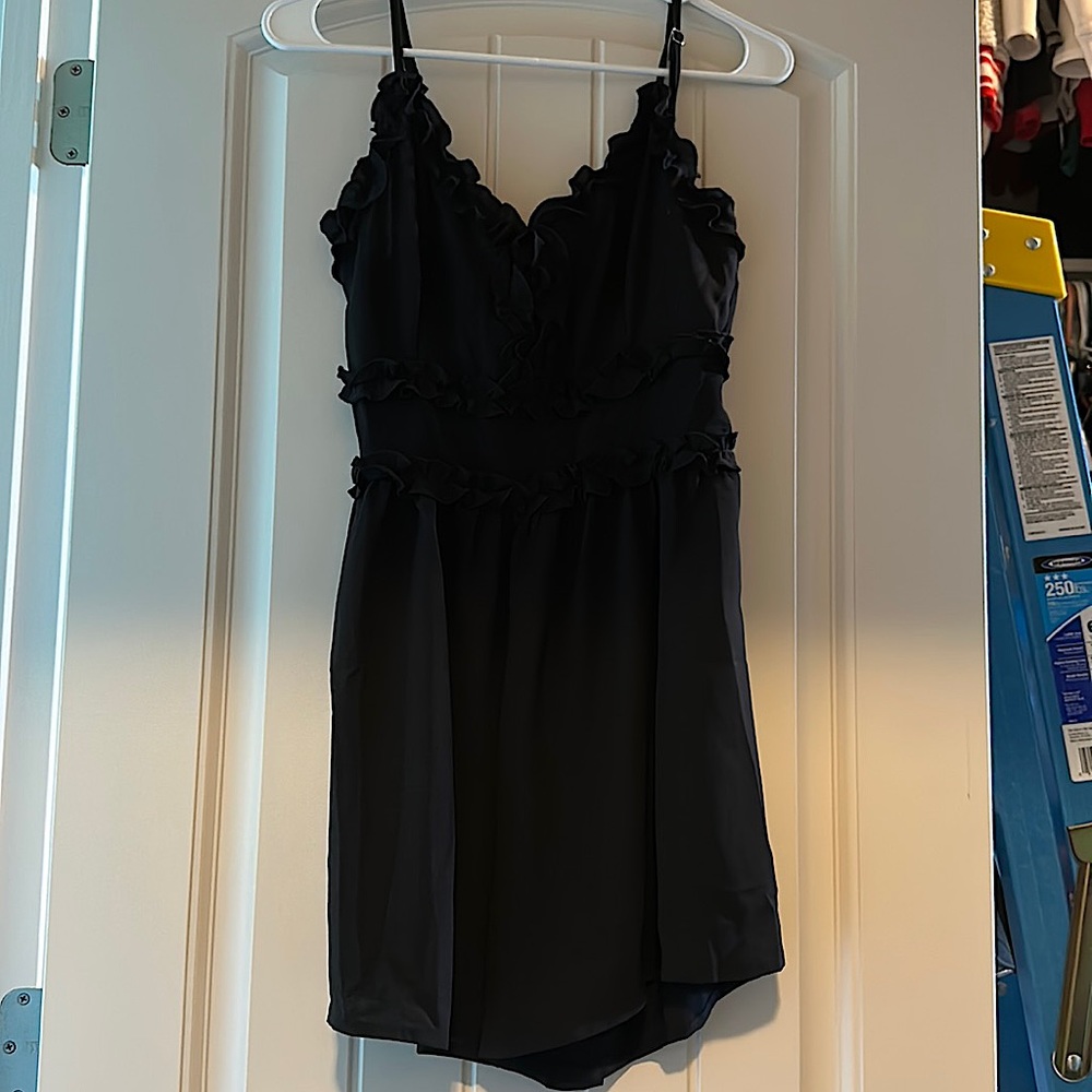 Black romper with ruffle detail and adjustable straps. Never worn.